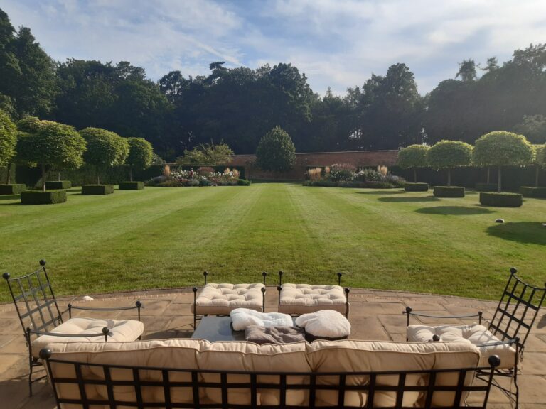 Freshly mowed main lawn with crisp summer stripes, creating a neat and professional garden appearance.